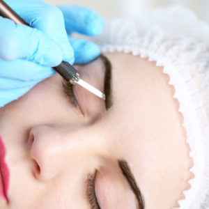 Cosmetologist applying permanent make up on eyebrows